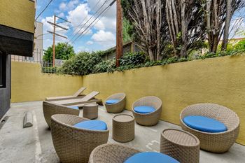 Community outdoor courtyard sitting area near BBQ with wicker chairs and lounge chairs.